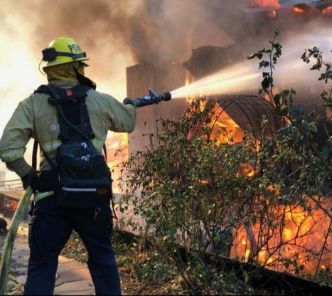 Poway firefighter spraying water on a fire