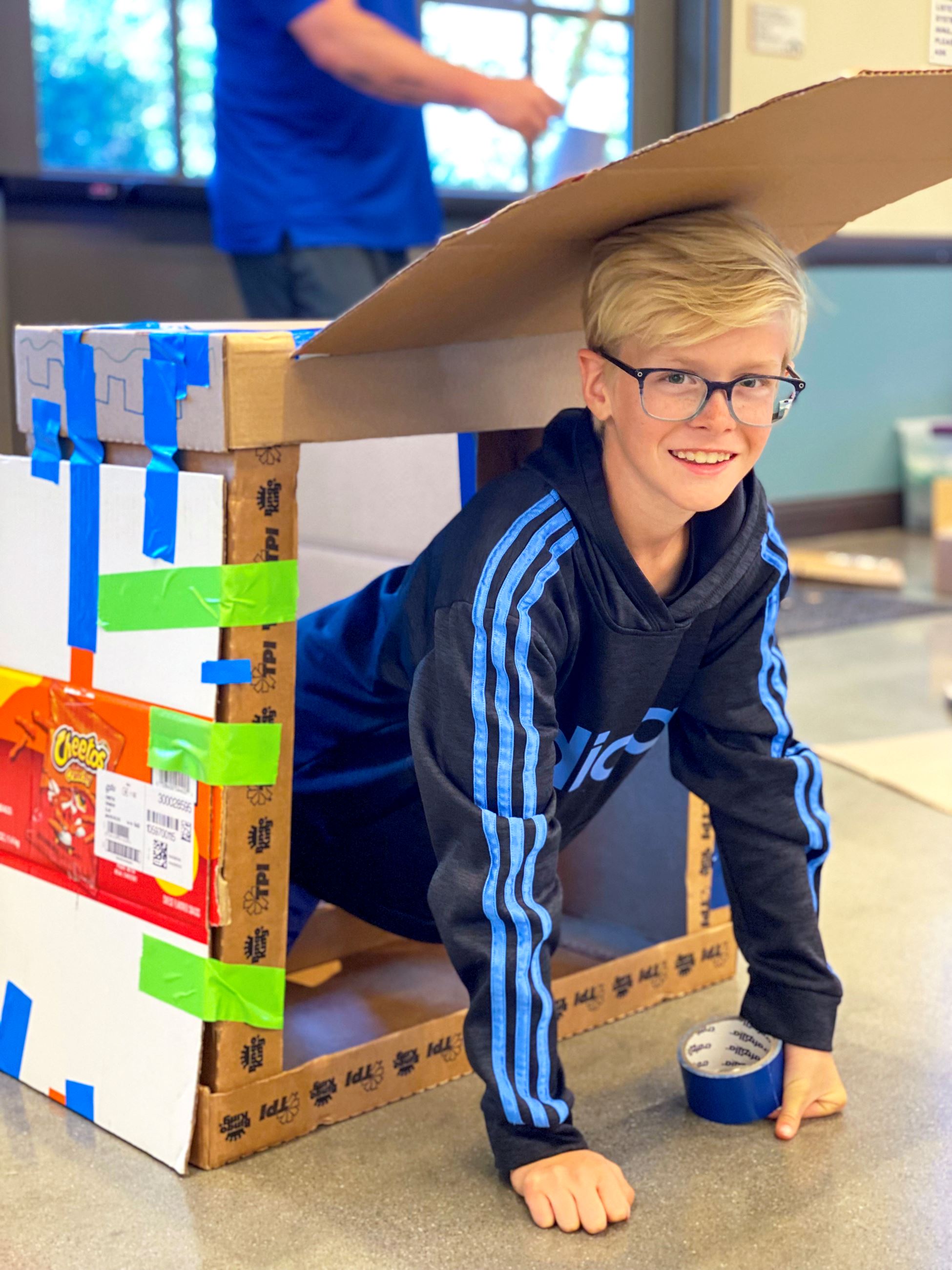 Blond boy climbing out of a cardboard box
